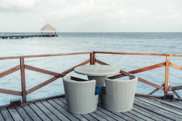 View from a coastal restaurant of a luxury Maldives resort with selective focus on a wicker cafe...