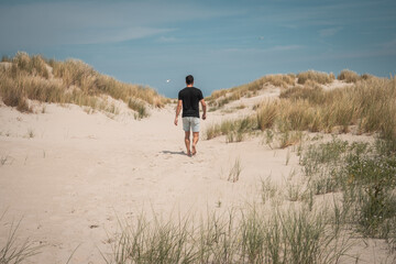 Young man (guy) going for a walk in the dunes and sand beach on the Northsea coast of the german...