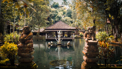 Pond with two guardians statues and a goddess playing music on the middle in Kawi Sebatu temple