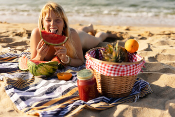 Cheerful young woman enjoy at tropical sand beach. Portrait of happy girl with fruit. Young woman having a picnic on the beach