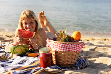 Cheerful young woman enjoy at tropical sand beach. Portrait of happy girl with fruit. Young woman having a picnic on the beach