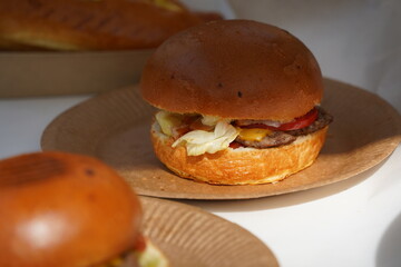 Freshly baked burger on a cardboard plate.