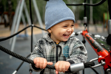 Obraz premium A kid in a gray plaid jacket is playing on a children's playground. The concept of a happy childhood