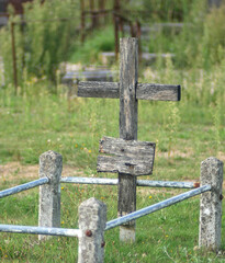 Slightly blurred wooden cross, worn out by time, on a grave, in an abandoned graveyard. Shot with vintage lens.