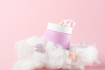 Composition with cosmetic cream jar marshmallows and cotton on pink background. Natural product for skin pampering. Lotion promotion