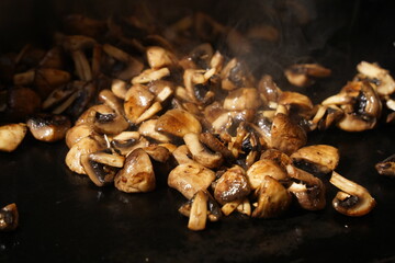 Roasting mushrooms on an open outdoor flat plate.