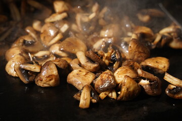 Roasting mushrooms on an open outdoor flat plate.