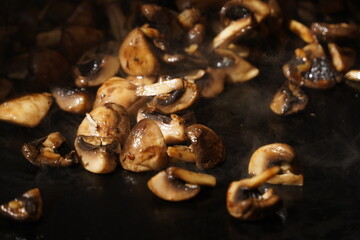 Roasting mushrooms on an open outdoor flat plate.