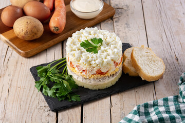 Traditional Russian layered salad Mimosa on wooden table