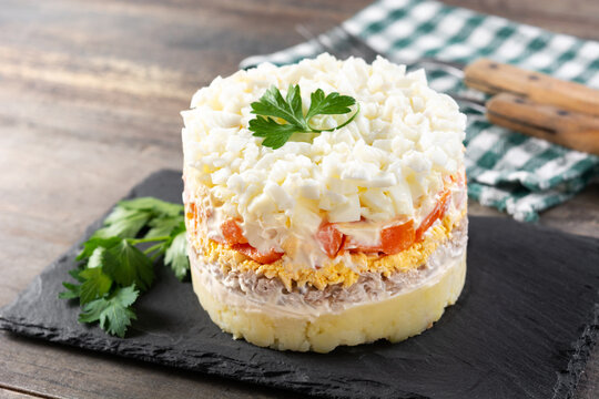 Traditional Russian layered salad Mimosa on wooden table