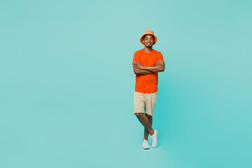 Fototapeta na wymiar Full body happy young man of African American ethnicity 20s wear orange t-shirt hat hold hansd crossed folded look camera isolated on plain pastel light blue cyan background. People lifestyle concept.