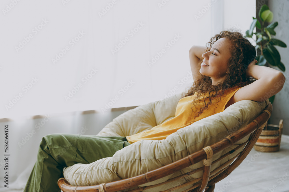 Wall mural side view fun young woman of african american ethnicity 20s wear casual clothes sits near window in 