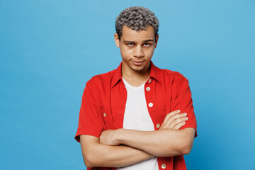 Young sad offended unhappy man of African American ethnicity 20s he wear red shirt hold hands...