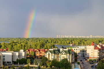 A real rainbow over the Dnieper river in Kiev during summer. Buildings of the Obolon district in the foreground, and in the background the buildings of the Troieshchyna district