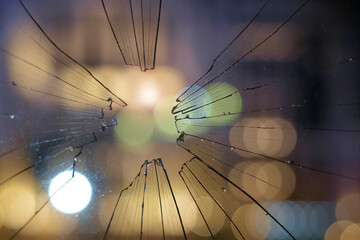 Blurred abstract city lights background behind the dirty broken glass