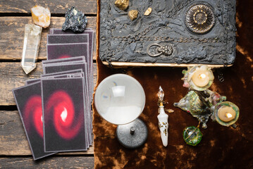 Tarot cards, crystal ball and book of magic on the old fortune teller desk table background. Future...