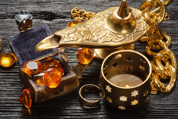 Magic lamp and jewels on the old wooden table background.