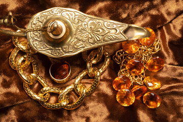 Magic lamp and jewels on the old wooden table background.