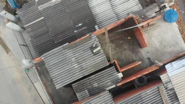 A running shot of favela where only roof of residential houses has been captured by drone. one car is seen being parked along side of a house