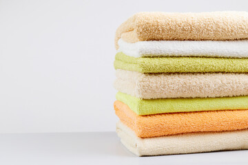 A stack of clean towels on a light gray background. Cotton towels on table. Space for text