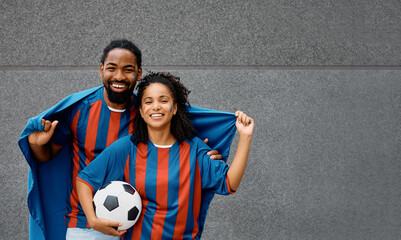 Happy black couple of soccer fans cheering during world cup and looking at camera.