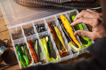 fisherman chooses silicone lure from tackle box