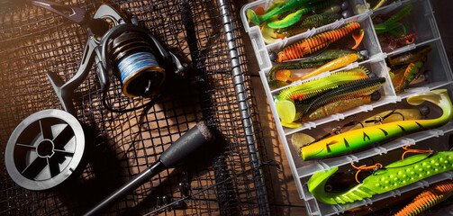 fishing tackle. rod, reel and lures box on wooden background. banner