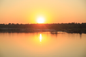 Landscape with bright orange sunset over the lake.