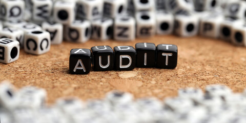 Closeup of word on plastic cube on wooden desk background concept- audit
