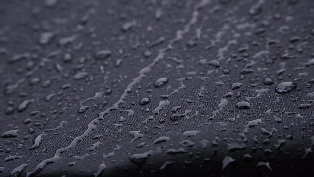 Heavy rain on black waterproof textile. 4K Close Up.