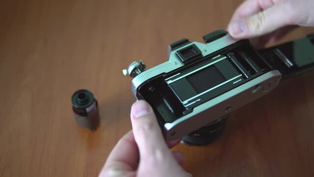 Loading color film into old analog SLR camera, 4K close up fast forward footage