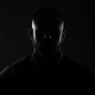 Backlight portrait hidden face in the shadow, male person silhouette on dark background