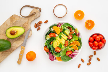 Cooking healthy green salad with avocado and tomatoes