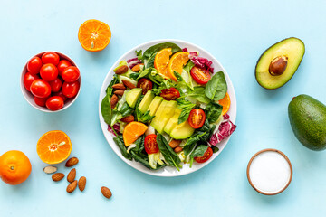 Cooking healthy green salad with avocado and tomatoes