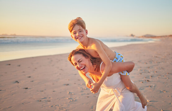 Mother, child and piggy back on beach on summer holiday walking in sea sand. Woman from Australia with son at the ocean. Mom, happy kid and sunset, family time with water, freedom and fun on vacation