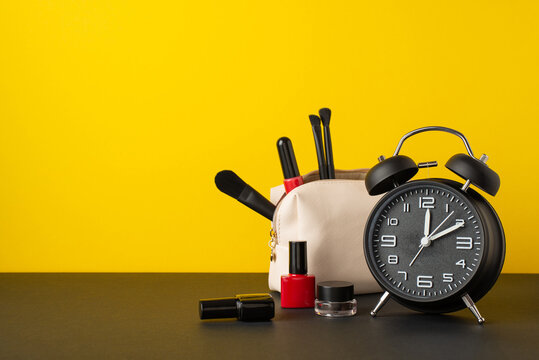 Black friday shopping concept. Photo of alarm clock cosmetic bag with brushes lip gloss eyebrow gel and nail polish on desktop yellow wall background