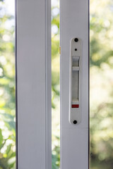 Close-up of a double-glazed balcony frame with a latch and fastening for safe ventilation. Single-sided window handle. House door and window repair concept