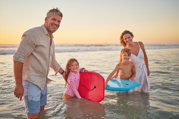 Fototapeta premium Family, beach and body board, kids with parents in water on summer holiday. Mom, dad and children surfing in ocean at sunset in Australia. Freedom, fun and vacation, happy man and woman play in waves
