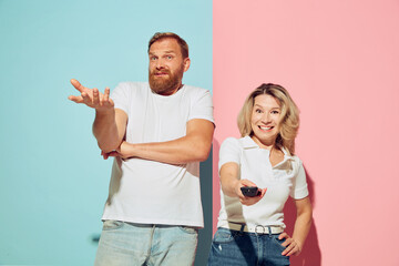 Emotional young couple, bearded man and pretty woman isolated over blue-pink studio background....