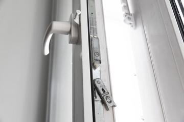 Close-up of a double-glazed balcony frame with a latch and fastening for safe ventilation. Single-sided window handle