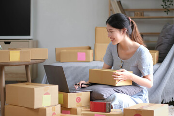 Shipping shopping online ,young start up small business owner writing address on cardboard box at...