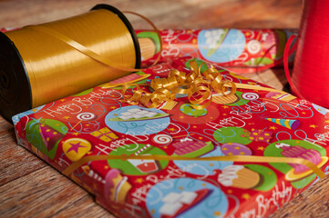 Fototapeta na wymiar Wrapped birthday gift with wrapping material on a wooden table.