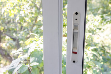 Close-up of a double-glazed balcony frame with a latch and fastening for safe ventilation. Single-sided window handle. House door and window repair concept