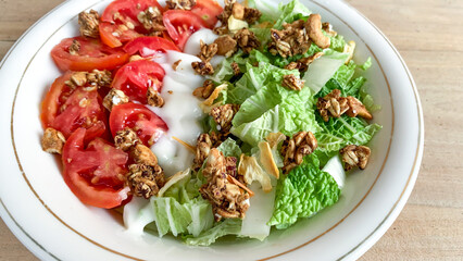 bowl of vegetable salad with chinese cabbage, tomato with mayonnaise dressing and granola as topping.