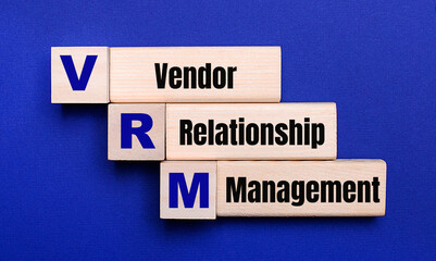 On a bright blue background, light wooden blocks and cubes with the text VRM Vendor Relationship Management