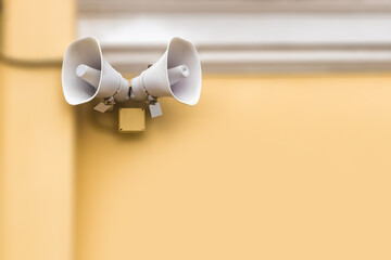 Danger warning system. Two white loudspeakers on a yellow wall. Notification of emergency...