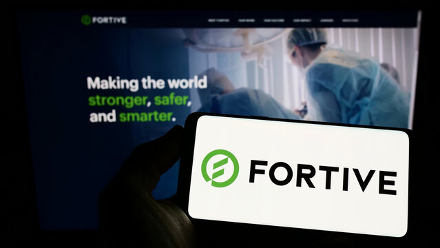 Stuttgart, Germany - 09-25-2022: Person holding smartphone with logo of US technology company Fortive Corporation on screen in front of website. Focus on phone display.