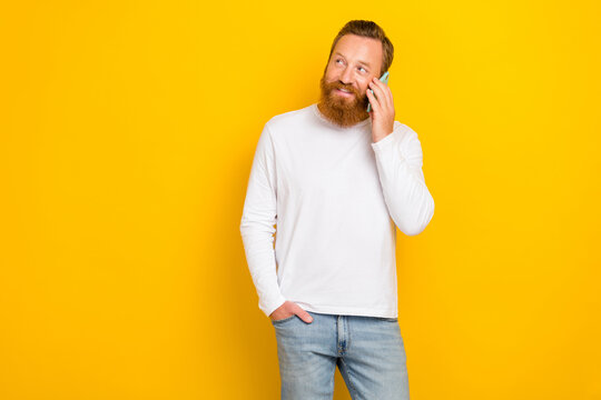 Portrait Photo Of Young Redhair Man Solid Worker Influencer Talking Phone User Look Empty Space Advert Isolated On Yellow Color Background