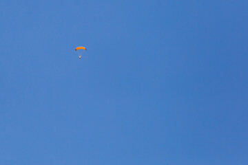 Skydiver with a little canopy of a parachute on the background a blue sky, close-up. Skydiver under parachute
