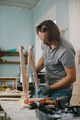 A carpenter makes wooden toys in a carpentry workshop. Making a bed carousel.